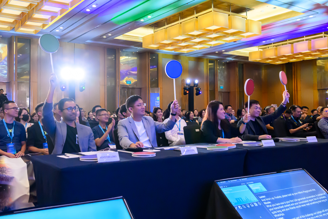 Picture of the judges lifting up their judging sticks at the prompt royale 2025 finale held as part of GovTech innovation day